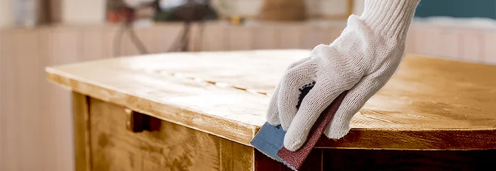 Person schleift einen Holztisch